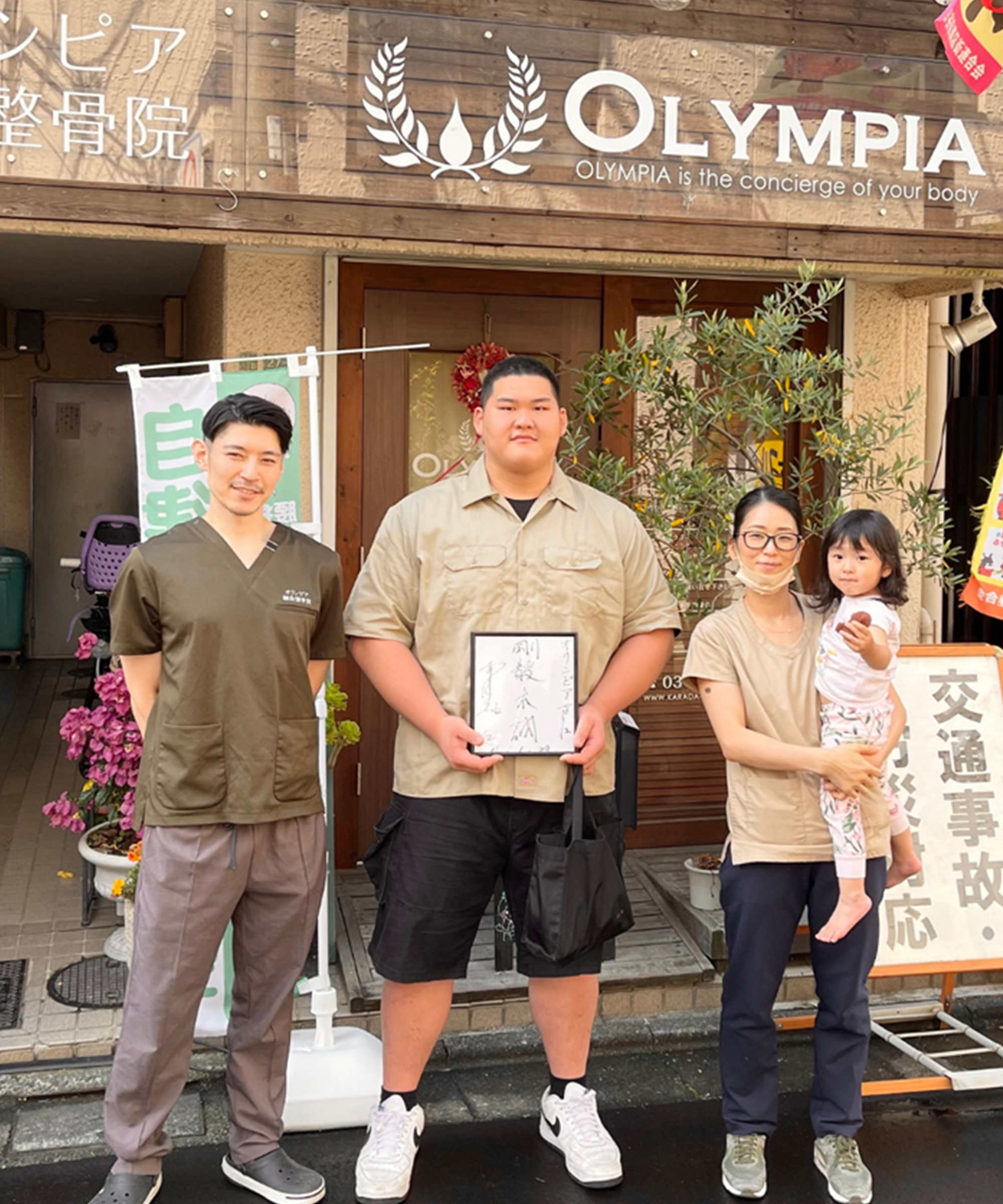 3人が店の前に立っているの画像